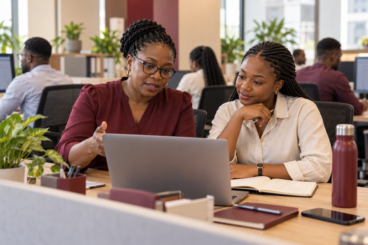 An HR manager helping a colleague at a workstation in Accra